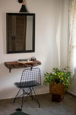 a mirror on a wall with a chair and a plant at Anassa Mountain House in Émbonas