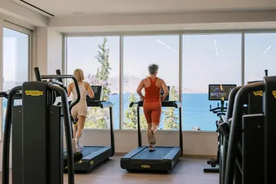 two women running on treadmills in a gym at Lindos Mare, Seaside Hotel in Líndos