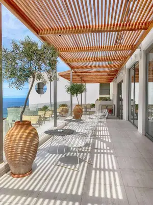a patio with a table and chairs and a tree at Lindos Mare, Seaside Hotel in Líndos