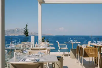 a restaurant with tables and chairs and a view of the ocean at Lindos Mare, Seaside Hotel in Líndos