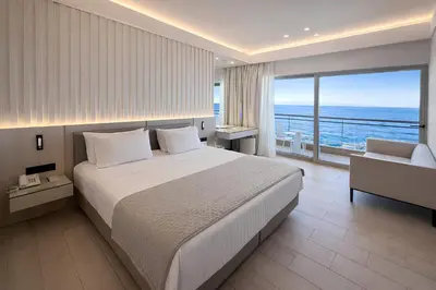 a bedroom with a large bed and a view of the ocean at Mediterranean Hotel in Rhodes Town