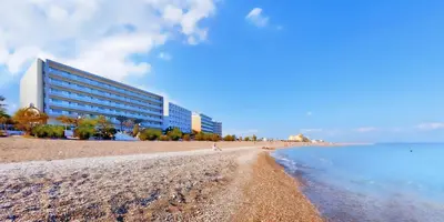 a building on a beach next to the water at Mediterranean Hotel in Rhodes Town