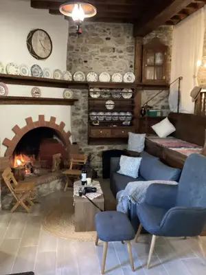 a living room with a stone fireplace and blue chairs at Casa Charma in Émbonas