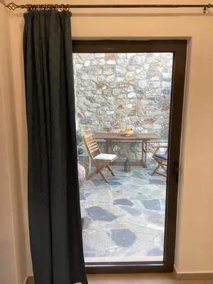 a door to a patio with a table and a stone wall at Casa Charma in Émbonas