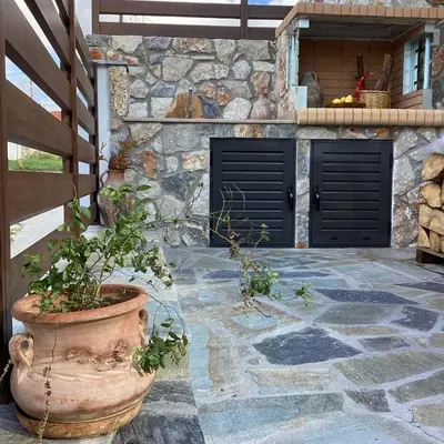 a stone building with two black doors and a potted plant at Casa Charma in Émbonas