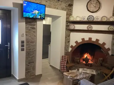a living room with a fireplace and a tv on a wall at Casa Charma in Émbonas