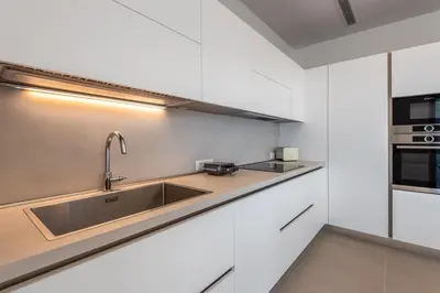 a kitchen with white cabinets and a sink at Ialyssos Charme Villa in Ialyssos
