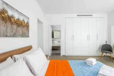a white bedroom with a bed and a painting on the wall at Ialyssos Charme Villa in Ialyssos