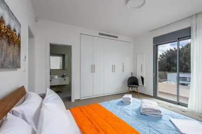 a white bedroom with a bed and a bathroom at Ialyssos Charme Villa in Ialyssos