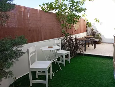 a patio with white chairs and a table and grass at MARY'S APARTMENT in Paradissi in Paradeísion