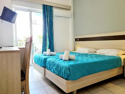 a bedroom with a bed with blue sheets and a window at G92 City Hotel in Rhodes Town