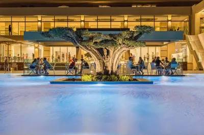 a tree in the middle of a pool in a building at Amada Colossos Resort in Faliraki
