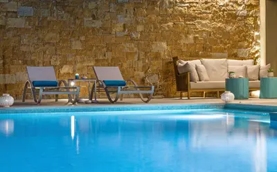 a hotel pool with two chairs and a couch at Amada Colossos Resort in Faliraki