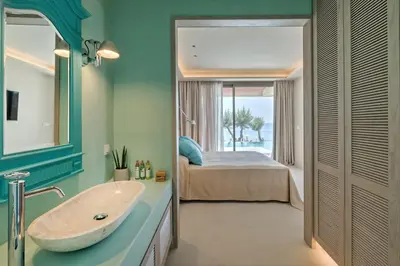 a bathroom with a sink and a bedroom with a bed at Amada Colossos Resort in Faliraki