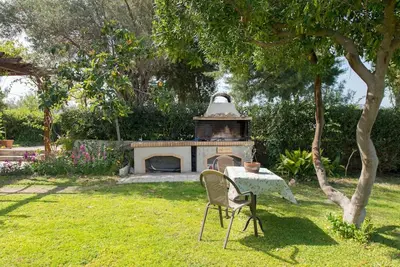 a table and chairs in a yard with a fireplace at Garden House with sea view in Faliraki