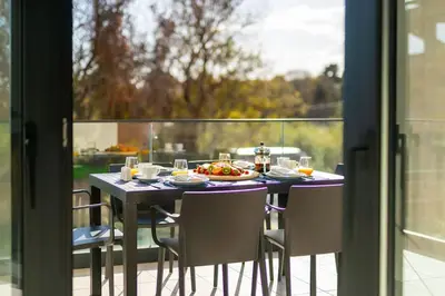 a table with a plate of food on a balcony at Maison Du Jardin 2-Bedroom Apartment Private Outdoor Jacuzzi in Rhodes Town