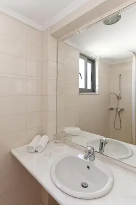 a white bathroom with a sink and a mirror at Hotel Africa in Rhodes Town