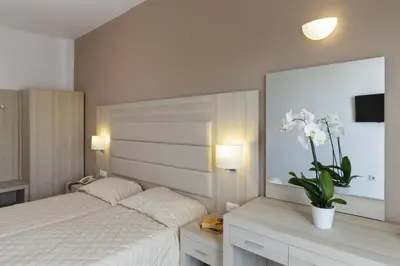 a bedroom with a bed and a vase with white flowers at Hotel Africa in Rhodes Town