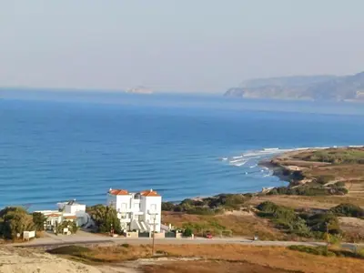 a white house on a hill next to the ocean at Pearl Villas Apolakkia - Beach Front Villas with Private Pool in Apolakkiá