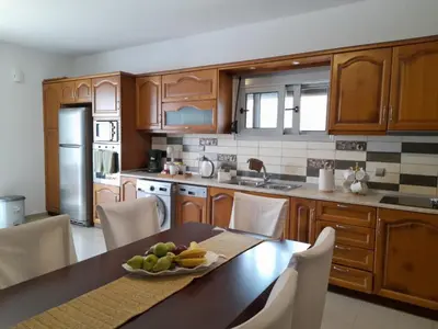 a kitchen with wooden cabinets and a table with a bowl of fruit at Pearl Villas Apolakkia - Beach Front Villas with Private Pool in Apolakkiá
