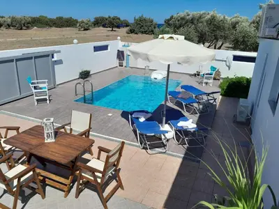 a patio with a table and chairs and a pool at Beach Pearl - Beach Front House with Private Pool in Gennadi
