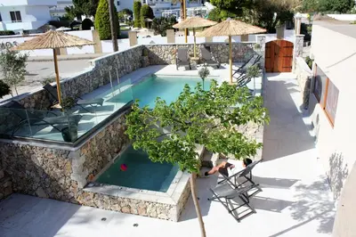 an infinity pool with a stone wall and chairs and umbrellas at John Mary in Faliraki