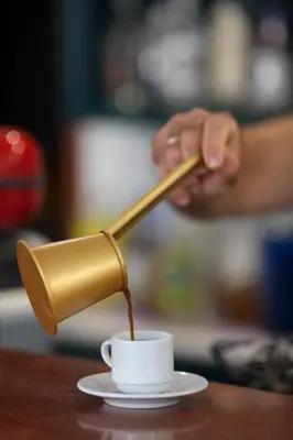 a person pouring coffee into a cup on a table at John Mary in Faliraki