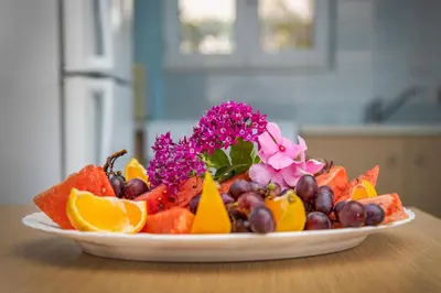 a plate of fruit and flowers on a table at Haraki Mare Studios beach front in Haraki