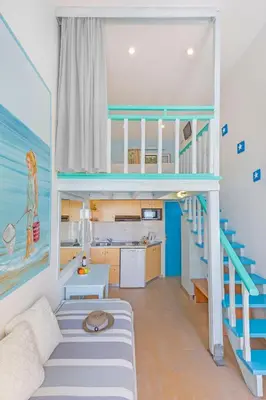 a living room with a staircase leading up to a bunk bed at Haraki Mare Studios beach front in Haraki