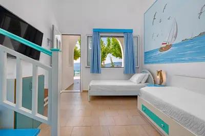 a bedroom with two beds and a tv and a window at Haraki Mare Studios beach front in Haraki