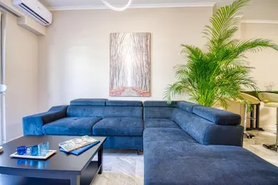 a living room with a blue couch and a table at Rhodes Island Elli Beach Apartments in Rhodes Town
