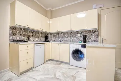 a kitchen with white cabinets and a washer and dryer at Rhodes Island Elli Beach Apartments in Rhodes Town