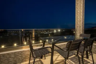 a table and chairs on a balcony at night at Sebastian Villas in Afantou