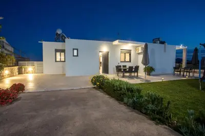 a white house with a patio at night at Sebastian Villas in Afantou