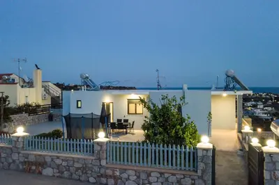 a small white house with a fence and lights at Sebastian Villas in Afantou