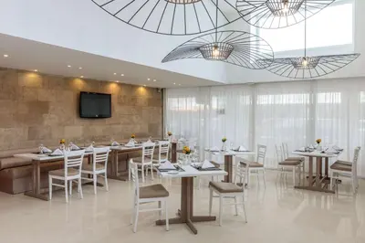 a restaurant with tables and chairs and a flat screen tv at Best Western Plus Hotel Plaza in Rhodes Town