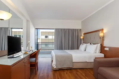 a hotel room with a bed and a desk with a television at Best Western Plus Hotel Plaza in Rhodes Town