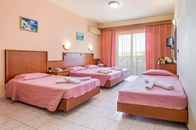 a hotel room with three beds with pink sheets at Alea Hotel Apartments in Ialyssos