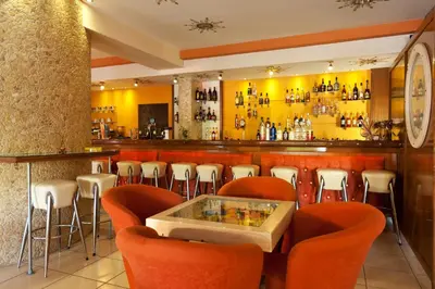 a restaurant with orange chairs and a bar at Alea Hotel Apartments in Ialyssos