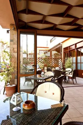 an outdoor patio with tables and chairs and windows at Alea Hotel Apartments in Ialyssos