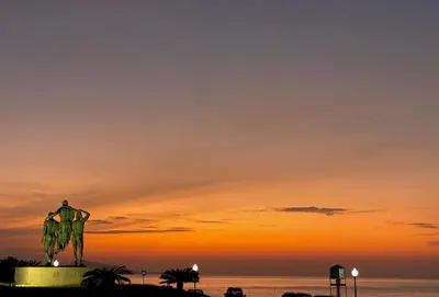 a statue of a man on the beach at sunset at Europa Hotel in Rhodes Town