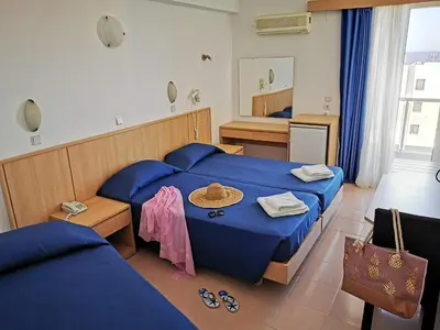 a hotel room with two beds and a mirror at Europa Hotel in Rhodes Town