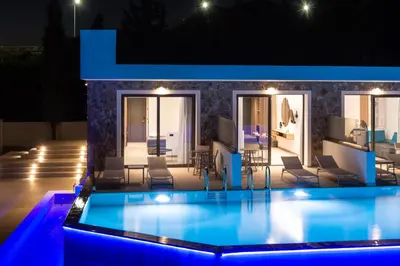 a swimming pool in front of a house at night at Zoes Hotel & Suites in Faliraki