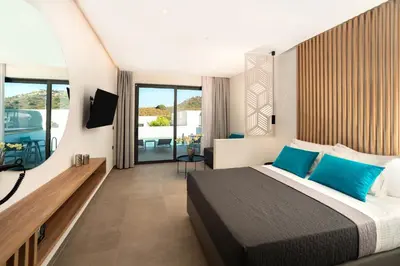 a bedroom with a large bed with blue pillows at Zoes Hotel & Suites in Faliraki