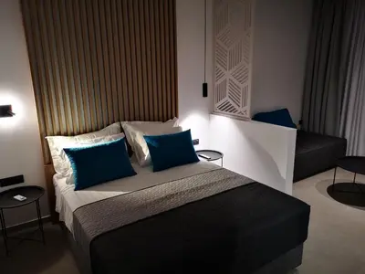 a bedroom with a large bed with blue pillows at Zoes Hotel & Suites in Faliraki