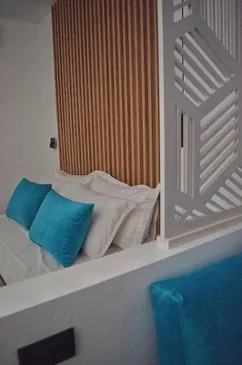 a bed with two blue pillows on top of it at Zoes Hotel & Suites in Faliraki