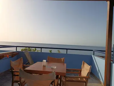 a table and chairs on a balcony with the ocean at Paraktio Beach Apartments in Kiotari