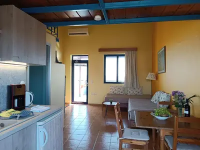 a kitchen and living room with a table and a couch at Paraktio Beach Apartments in Kiotari