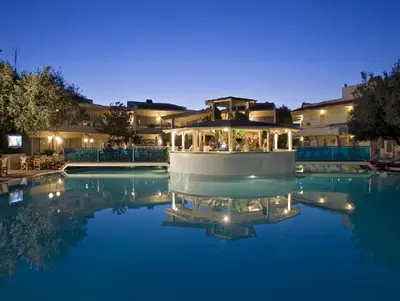 a house with a swimming pool at night at Lydia Maris Resort & Spa in Kolimbia