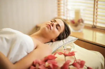 a woman laying in a bed with flowers on a table at Lydia Maris Resort & Spa in Kolimbia